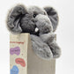 Gray plush elephant toy in a wooden box with text on a white background