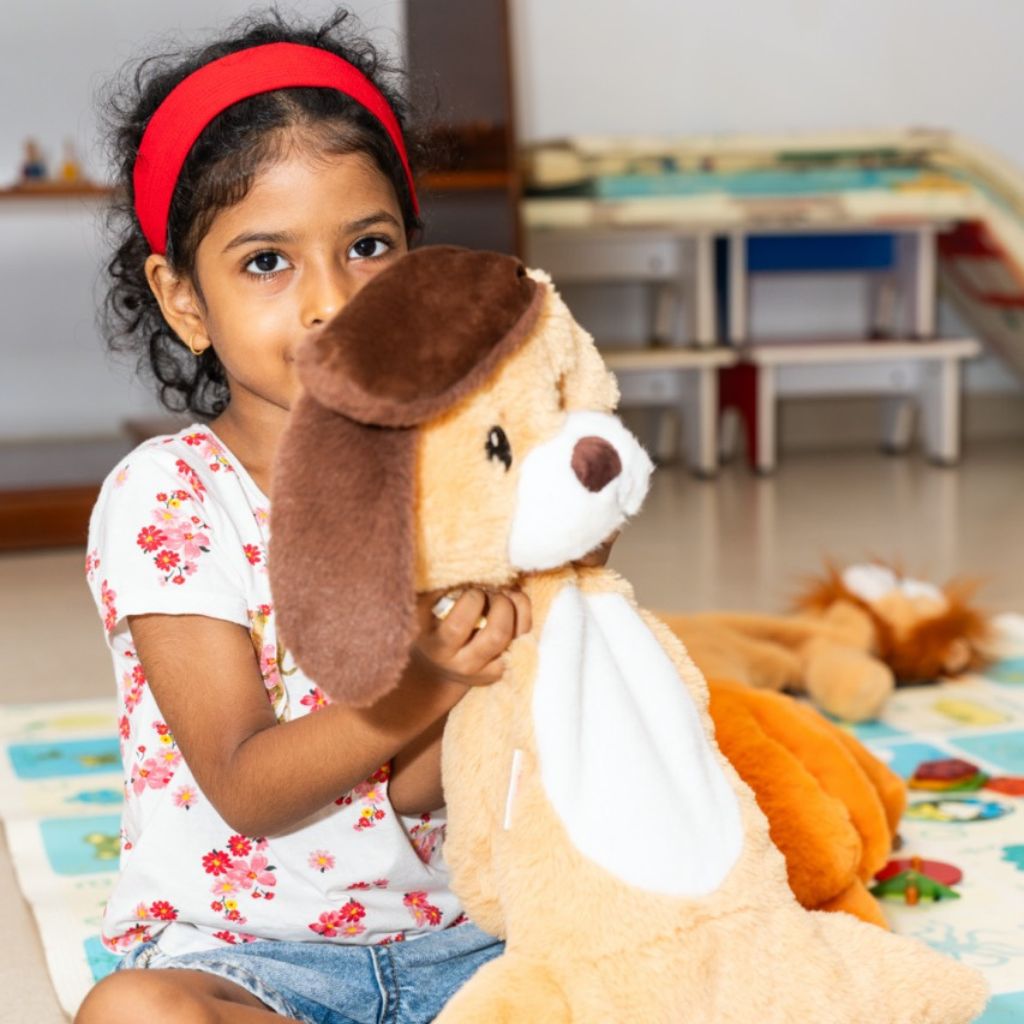 Young girl holding a dog soft toy in a classroom setting