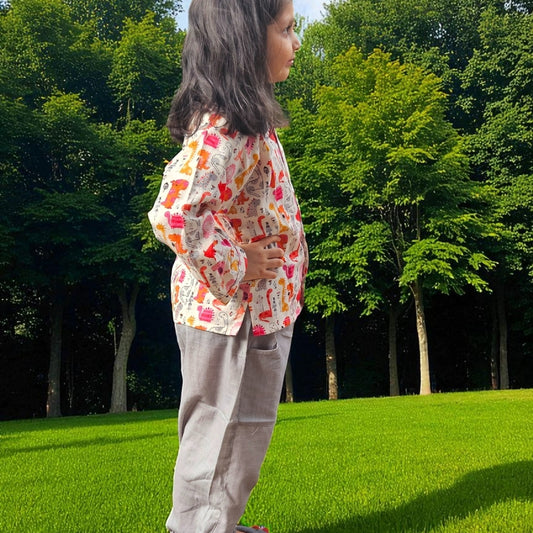 Person wearing a colorful patterned shirt and light gray pants standing on grass with trees in the background