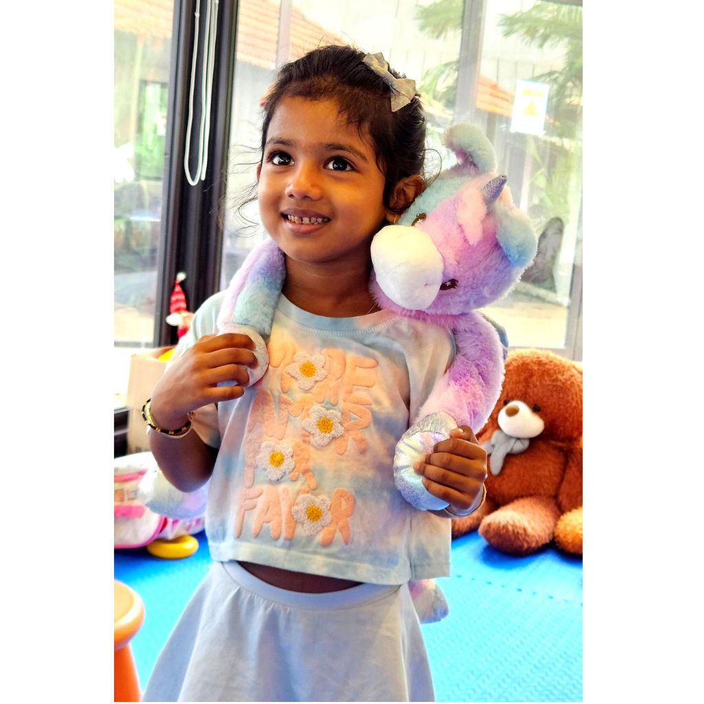 Child holding a colorful stuffed animal in an indoor setting