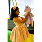 Young girl in a peach dress holding a pink unicorn plush toy on a green floor.
