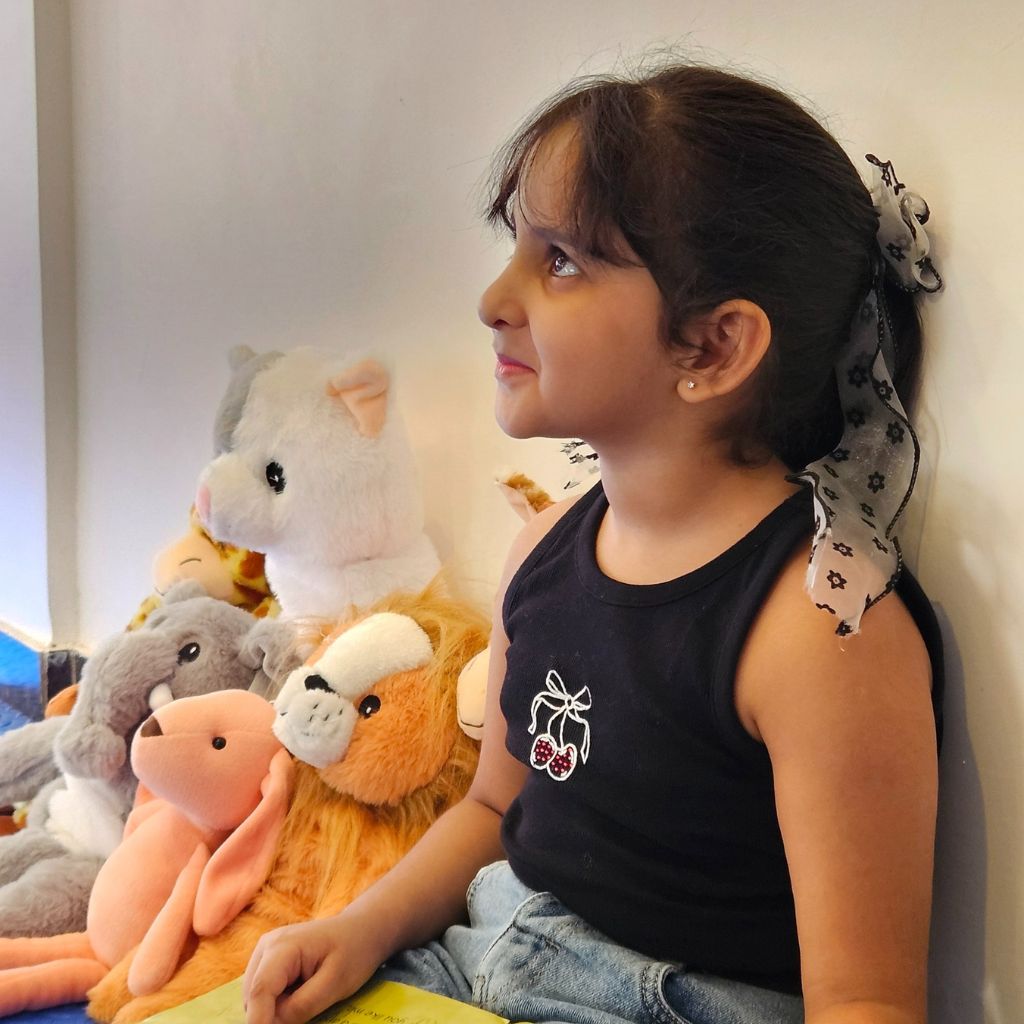 Child sitting with stuffed animals on a shelf